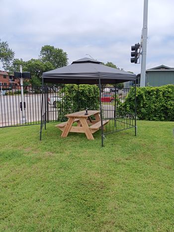 A picnic table is set up under a canopy in a grassy area.